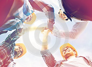 Close up of builders in hardhats making high five