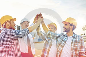 Close up of builders in hardhats making high five