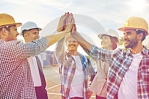 Close up of builders in hardhats making high five