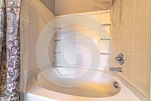 Close up of a built in oval bathtub inside a bathroom with white tiles on wall