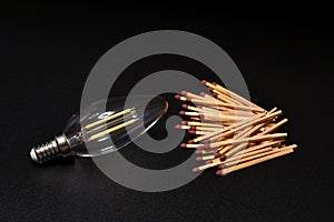 Close-up on a bulb light with matches on a black background. electricity supply problem concept. blackout