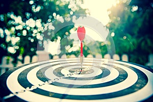 Close-up the bullseye target or dart board has red dart arrow throw hitting the center of a shooting