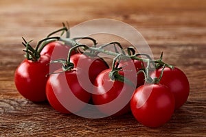 Close-up of a bunch of fresh cherry tomatoes on rustic wooden background, top view, shallow depth of field.