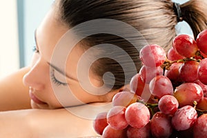 Close up bunch of red grapes with girl in background.
