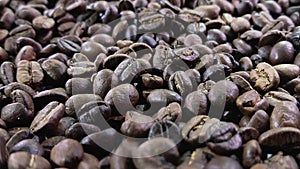 Close-up of bunch of roasted coffee beans falling on the coffee texture