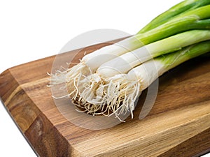 Close-up of bunch of spring onions laying on wooden board