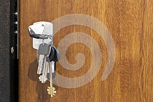 Close-up of bundle of different keys in key hole in wooden texture door.