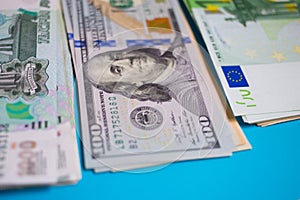 close up bundle of money Euros, dollars, rubles banknotes on the blue background, business, finance, saving, banking concept