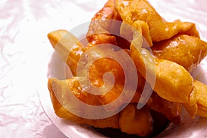 Close up of bunuelos served on a white plastic plate doused in honey