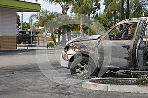 Close up a burned car in a parking lot with melted tire and no windows