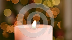 Close-up Burning candle on Christmas night. Festive candlelight with tranquil bokeh lights on dark background