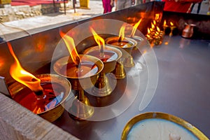 Close up of burning candles inside golden goblets in a temple. Kathmandu, Nepal, Asia