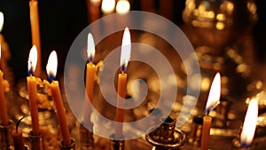 Close up burning candles in the Orthodox church. Memorial wax candles flicker with fire flame on large gold candlestick