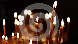 Close up burning candles in the Orthodox church. Memorial wax candles flicker with fire flame on large gold candlestick