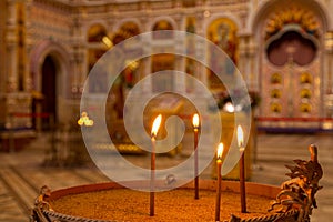 Close-up of burning candles standing in cup with sand in christian church