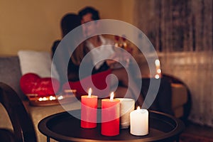 Close up of burning candles. Valentines Day couple celebrating love at home drinking wine