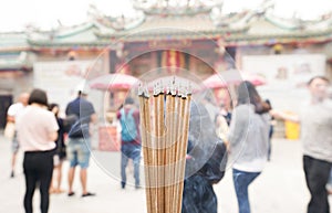 Close up burning incense sticks in front of a temple