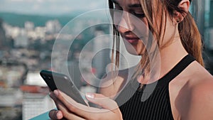 Close -up business busy girl with open shoulders. Young woman clicks on the phone buttons of skyscrapers on the