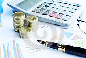Close up of Business fountain pen and coins stack and calculator on document chart backgrounds