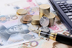 Close up of Business fountain pen and coins stack and china banknote