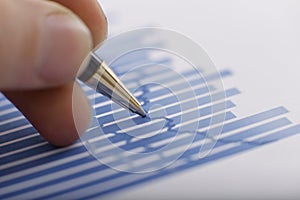 Close-up of business graphs and a male hand with a pen.