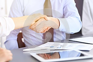 Close-up of business handshake at meeting or negotiation above the desk in office. Partners shaking hands while