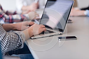 Close up of business man hands typing on laptop with team on mee