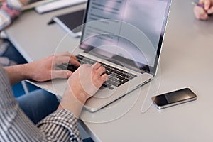 close up of business man hands typing on laptop with team on meeting in background