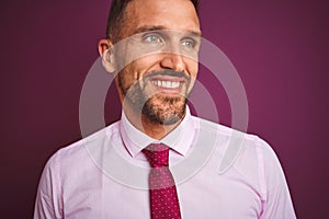 Close up of business man wearing elegant shirt and tie over purple isolated background looking away to side with smile on face,