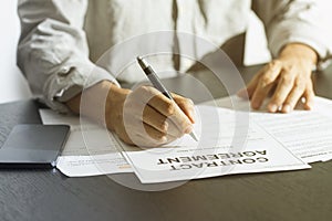 Close up of business manager signing document on table.