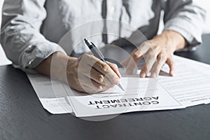 Close up of business manager signing document on table.