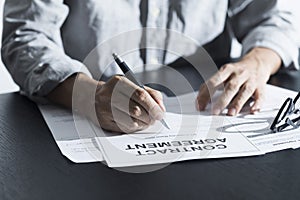 Close up of business manager signing document on table.