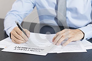 Close up of business manager signing document on table.