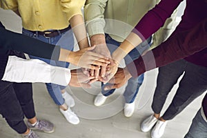 Close-up of business people or friends putting hands together as symbol of cooperation, teamwotk, unity