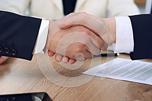 Close up of business people shaking hands at meeting or negotiation in the office. Partners are satisfied because