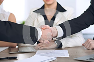Close up of business people shaking hands at meeting or negotiation in the office. Partners are satisfied because