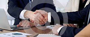 Close up of business people shaking hands at meeting or negotiation in the office. Partners are satisfied because photo