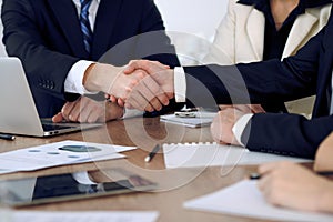 Close up of business people shaking hands at meeting or negotiation in the office. Partners are satisfied because