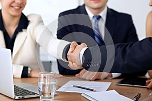 Close up of business people shaking hands at meeting or negotiation in the office. Partners are satisfied because