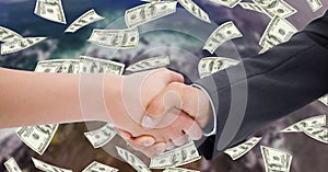 Close-up of business people shaking hands with money in background