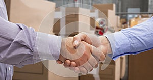 Close-up of business people shaking hands in warehouse