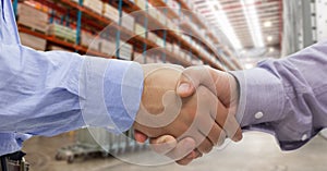 Close-up of business people shaking hands in warehouse