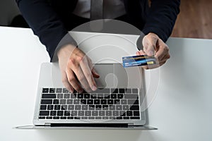 A close-up of a business person using a credit card and a laptop, technology