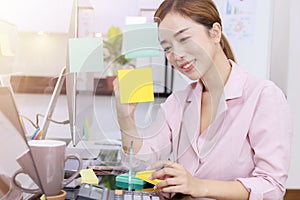 Close up business start up successful smile woman writing note on post-it at office. Businesswoman brainstorm writing note on blue