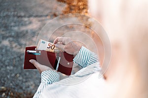 Close up of business style female hands holding a red leather wallet with 50 euro banknotes