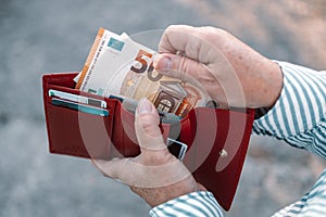 Close up of business style female hands holding a red leather wallet with 50 euro banknotes