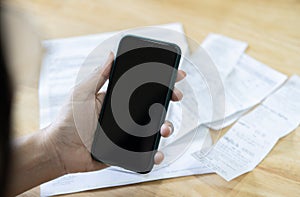 Close up of business woman hand uses her phone to pay his monthly credit card bill after receiving an invoice