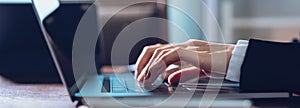 Close up of business woman hands typing on laptop computer and searching web, browsing in the workplace at office.