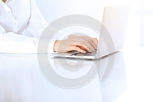 Close-up of business woman hands typing on laptop computer. Secretary at work in office