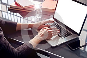 Close-up of business woman hands using working on laptop at co-working open space loft, mobile smartphone, metallic cold interior.